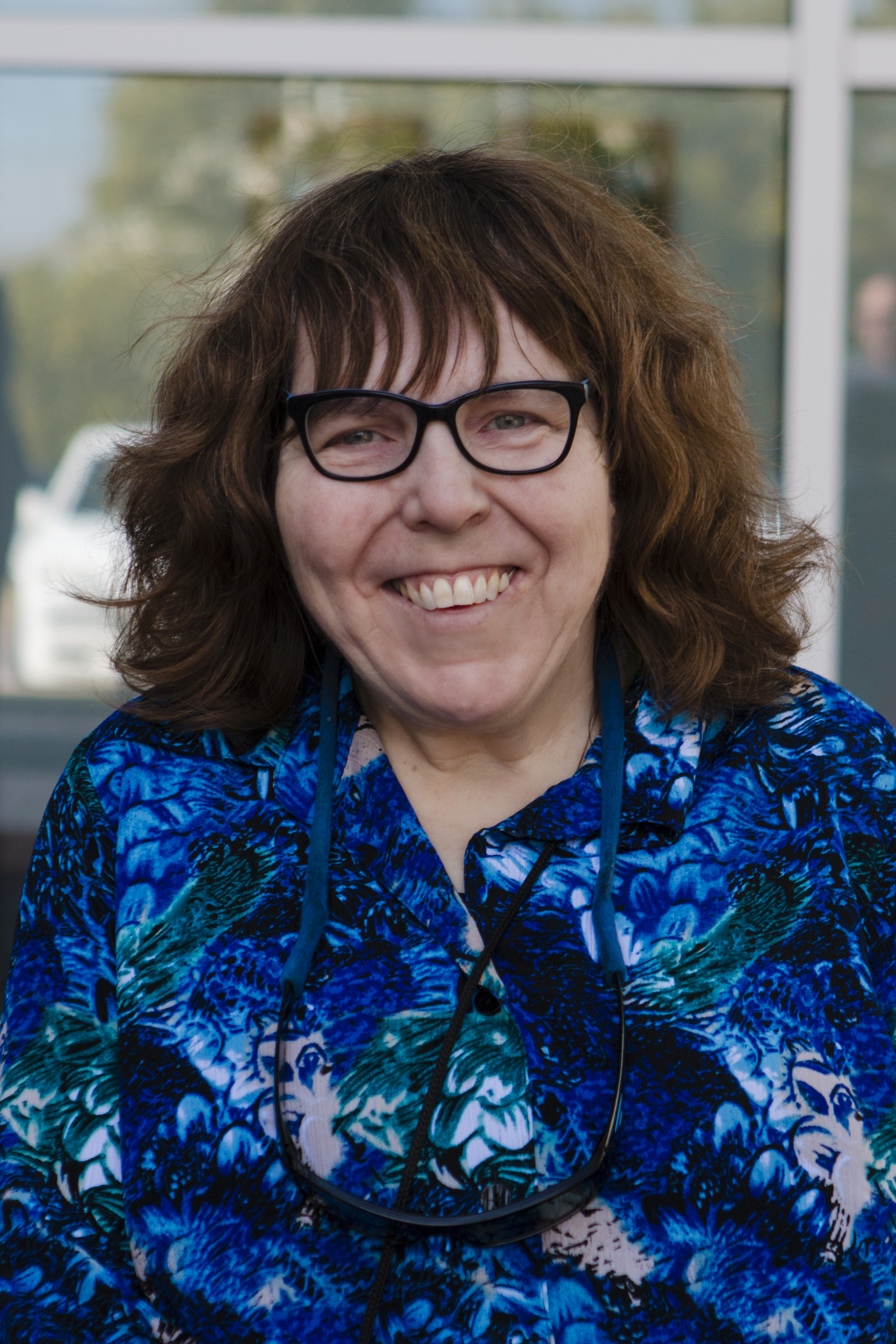Image of Nancy Ward, a white woman with brown hair and glasses wearing a blue floral collared shirt